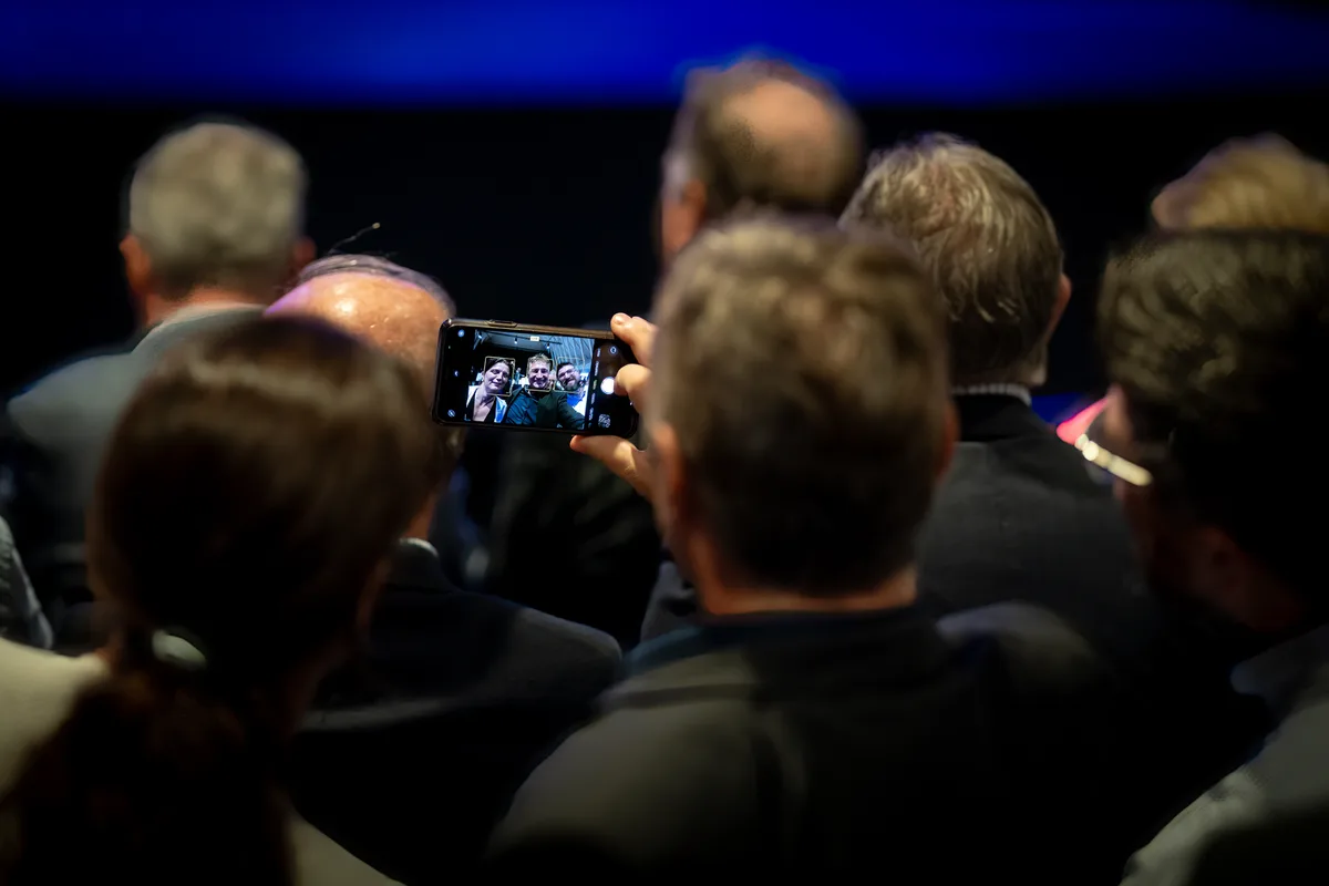 Drei Personen im Publikum machen ein Selfie. 